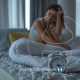 Mulher está sentada na cama, de madrugada, porque sofre de distúrbios do sono.
